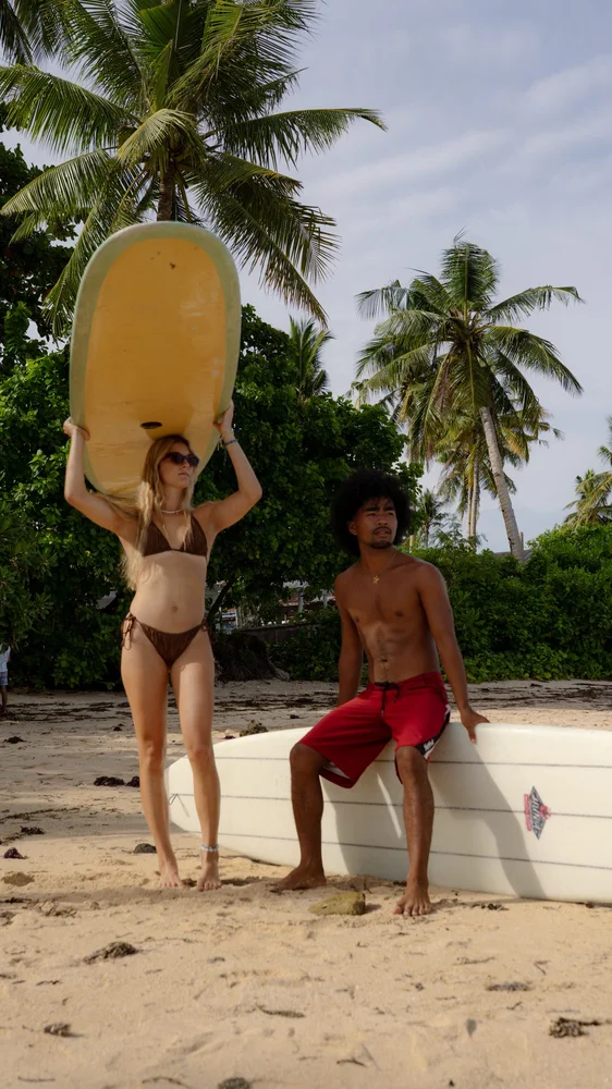 Group of surfers walking under palm trees at golden hour, Siargao